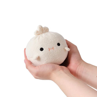 Small plush toy resembling a dumpling held in hands against a white background
