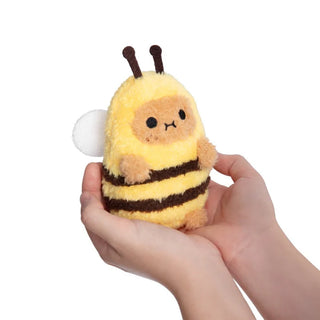 Plush bee toy held in a hand against a white background