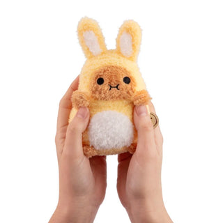 Hands holding a plush potato toy dressed as a yellow bunny on a white background