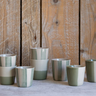 Set of ceramic cups with green and White stripes against a wooden background