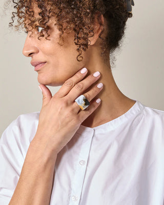 Woman wearing a white shirt and marbled ring with a neutral background