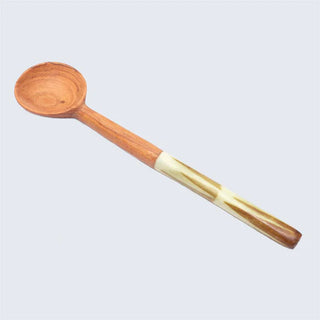 Wooden spoon with a olive green accent handle on a light gray background