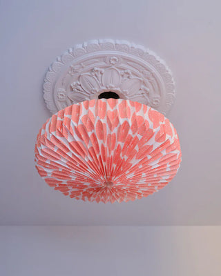 Decorative orange and white round origami ceiling light shade on a white ceiling