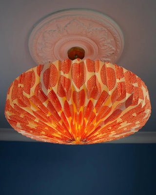 Decorative orange and white ceiling light shade with intricate circular design on a ceiling with the light on