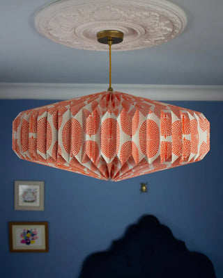 Side view of a saucer shaped orange and white origami paper ceiling light shade 
