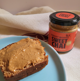 Sweet Chai Cashew Butter on a slice of bread with the jar of Sweet Chai in the background.