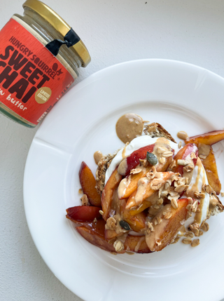 Plate of dessert with peaches, yogurt, and granola next to a jar of 'Sweet Chai' butter.