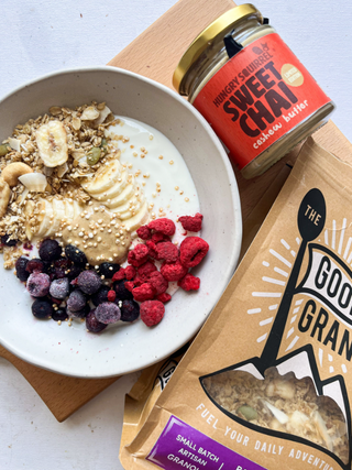Breakfast bowl with granola, yogurt, and berries next to a jar of sweet chai and a package of Granola.
