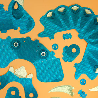 Blue pieces of the make your own triceratops mask laid flat against an orange background