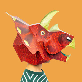 Red 3d paper triceratops mask on a child with a stripey tshirt against an orange background