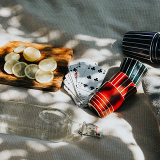 Playing cards, lemon slices on a wooden board, and colorful cups on a textured surface.