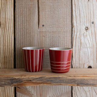 Two red striped cups on a wooden surface with a rustic wooden background