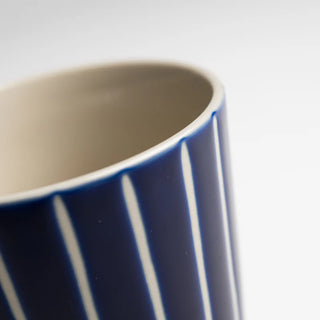 Close-up of a blue and white striped ceramic mug on a light gray background