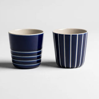 Two blue and white striped ceramic cups on a light gray background