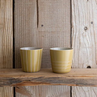 Two yellow ceramic cups on a wooden surface with a rustic wooden background