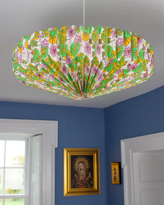 Decorative ceiling light fixture with floral pattern in a room with blue walls and framed pictures.