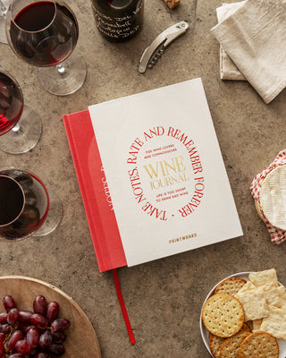 Wine journal on a table with wine glasses, grapes, and crackers.
