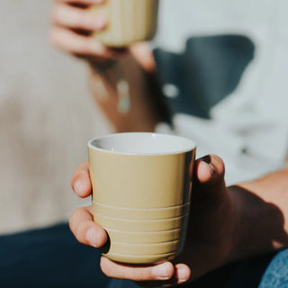 Person holding a yellow  mug with a blurred background